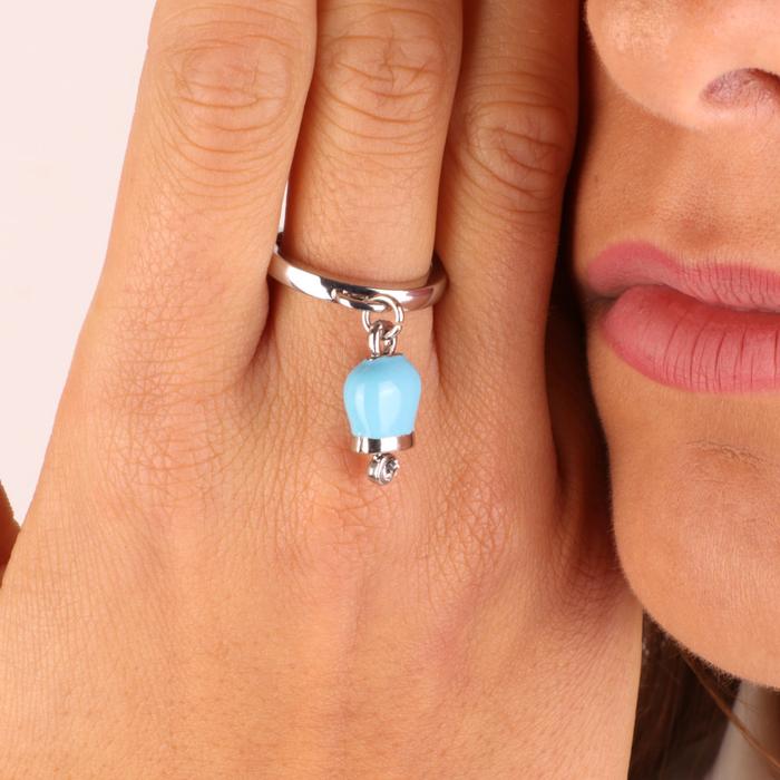 Bague en métal avec un pendentif porte-bonheur bleu, agrémenté d'un point lumineux